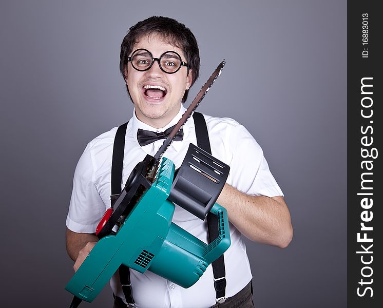 Portrait of mad fashion men in suspender with bow tie and glasses keeping portable saw. Studio shot. Portrait of mad fashion men in suspender with bow tie and glasses keeping portable saw. Studio shot.