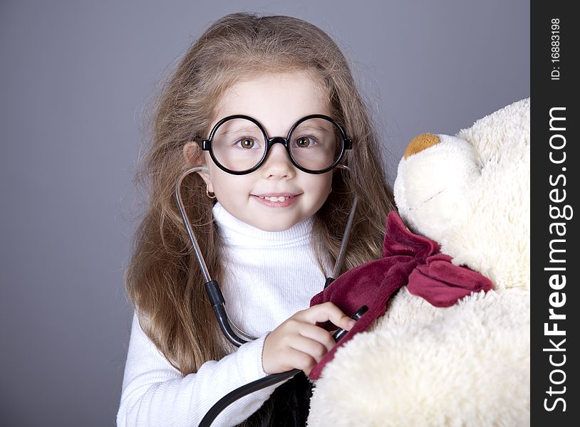 Little girl with  stethoscope and bear cub. Studio shot.