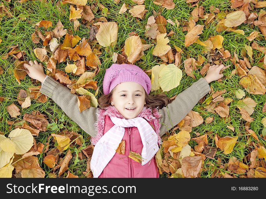 Little Girl At Grass And Leafs In The Park.