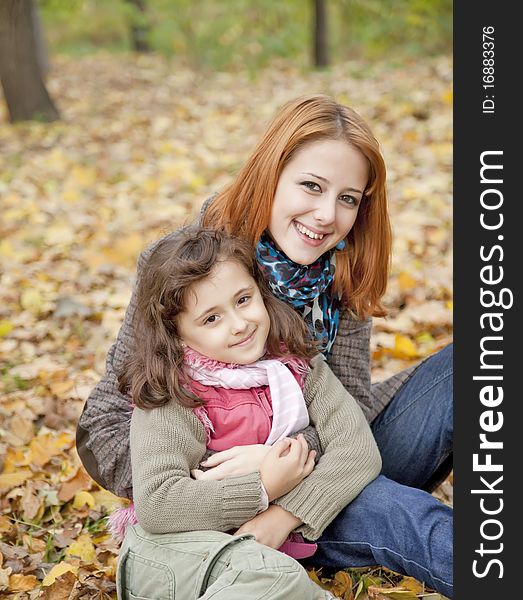 Two Sisters Sitting On The Leafs In The Park.