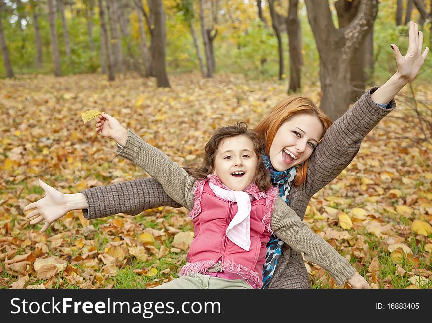 Two sisters sitting on the leafs in the park.