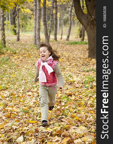 Cute running girl in autumn park. Portrait shot.