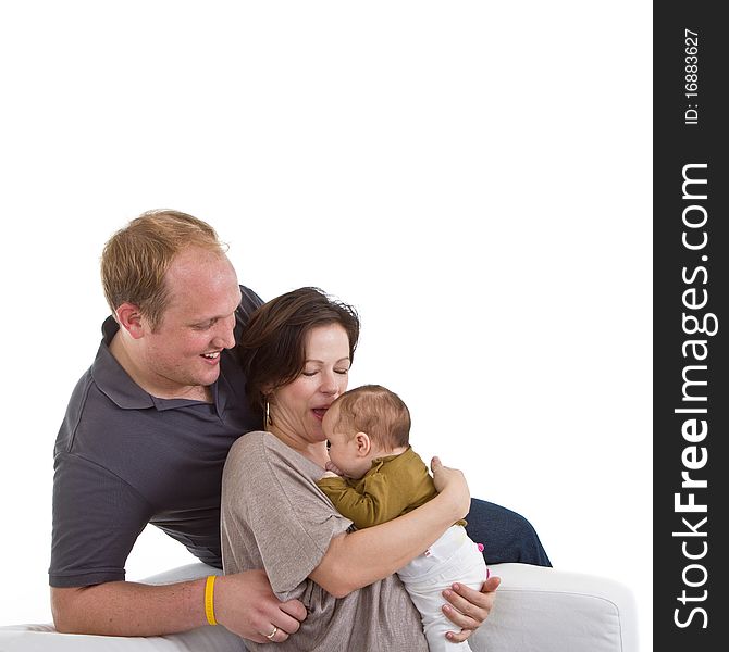 Young happy couple on a couch with their baby over white background. Young happy couple on a couch with their baby over white background.