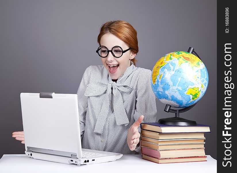 The young teacher in glasses with books, globe and notebook. Studio shot. The young teacher in glasses with books, globe and notebook. Studio shot.