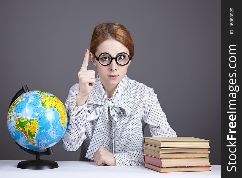 The young teacher in glasses with books and globe. Studio shot.
