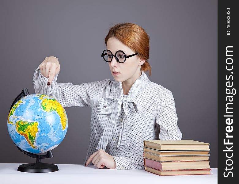 The young teacher in glasses with books and globe. Studio shot.