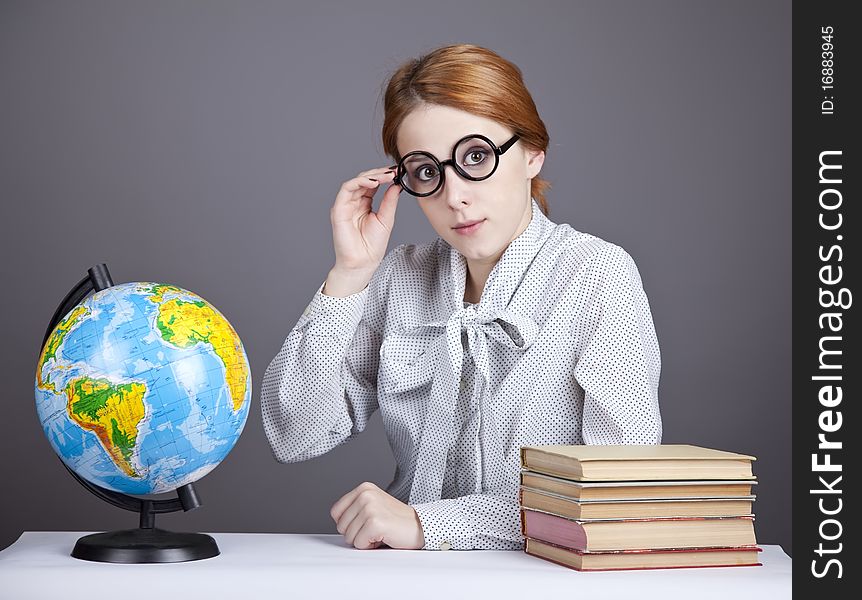 The young teacher in glasses with books and globe. Studio shot.