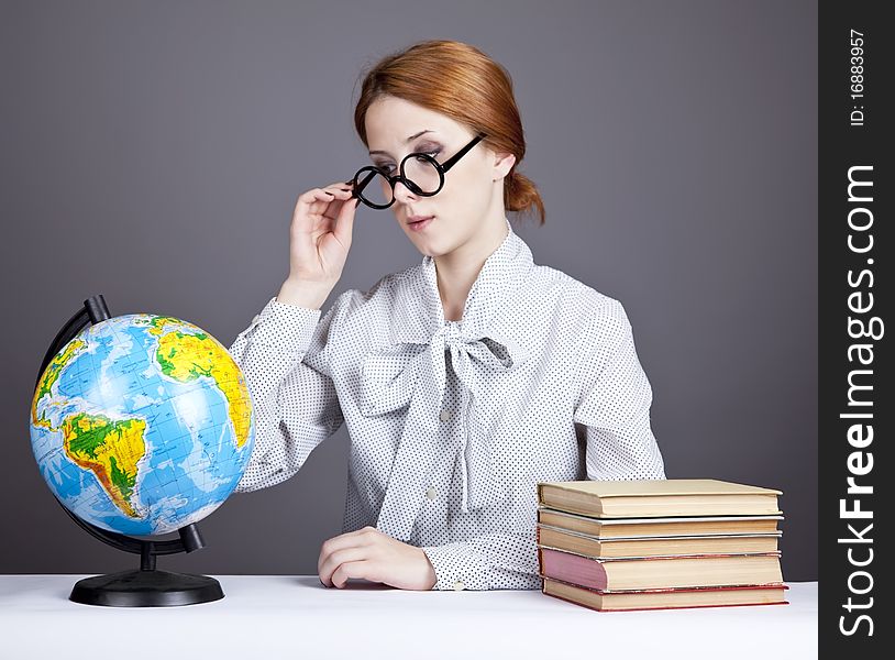 The young teacher in glasses with books and globe. Studio shot.