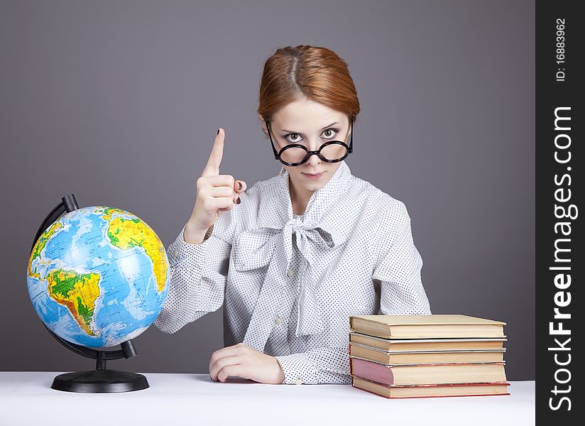 The young teacher in glasses with books and globe. Studio shot.