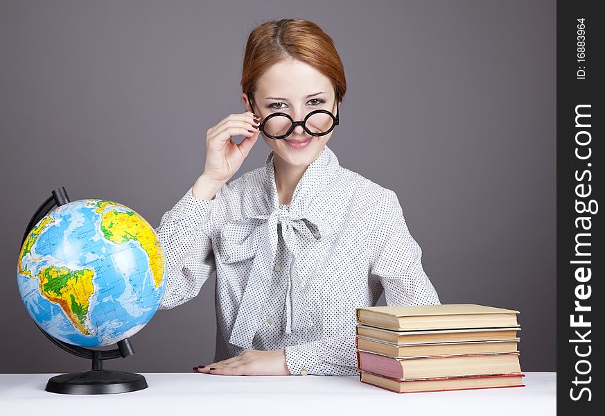 The young teacher in glasses with books and globe. Studio shot.