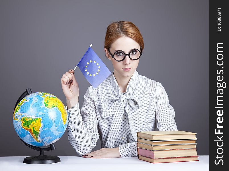 The young teacher in glasses with books and globe. Studio shot.