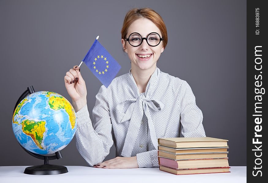 The young teacher in glasses with books and globe. Studio shot.