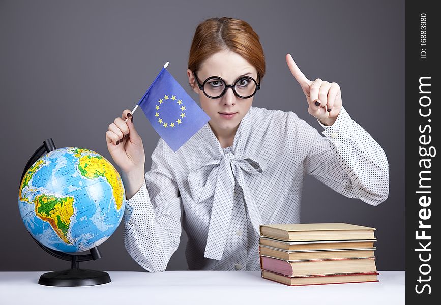 The young teacher in glasses with books and globe. Studio shot.