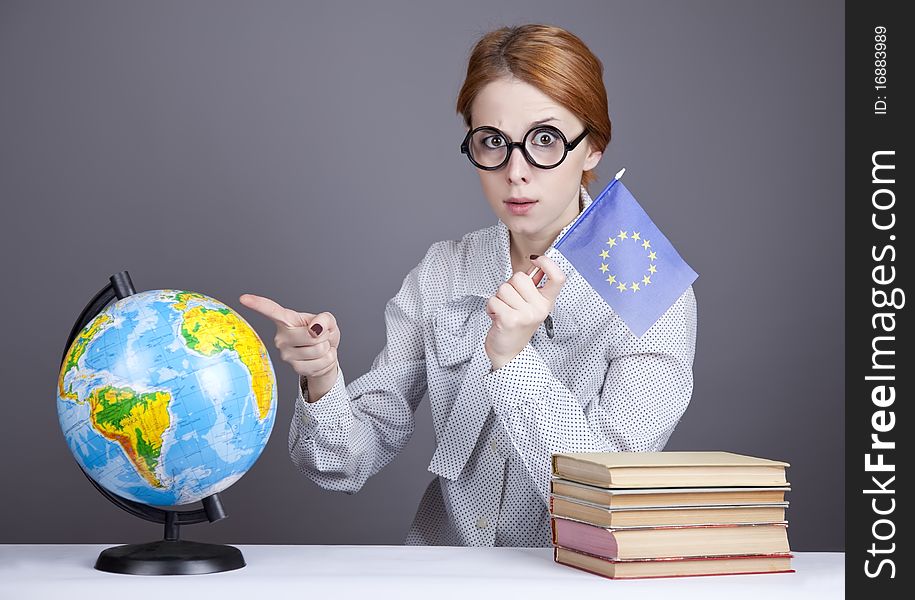 The young teacher in glasses with books and globe. Studio shot.