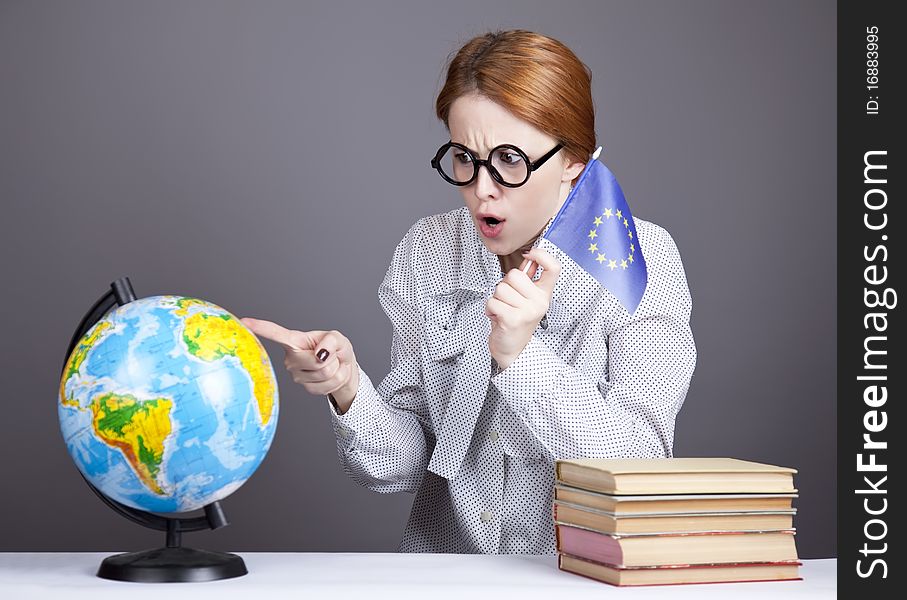 The young teacher in glasses with books and globe. Studio shot.