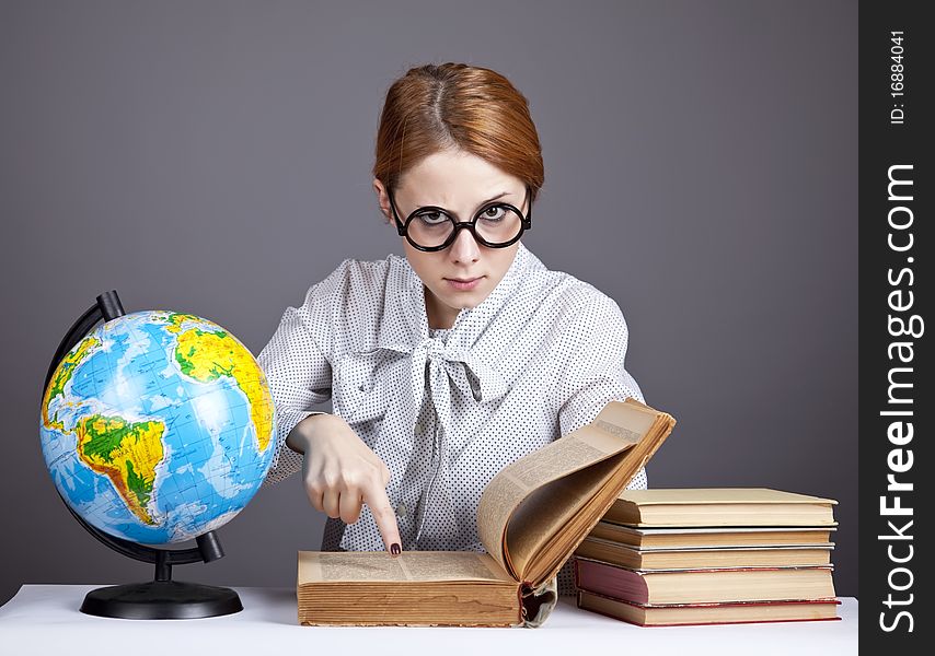 The young teacher in glasses with books and globe. Studio shot.