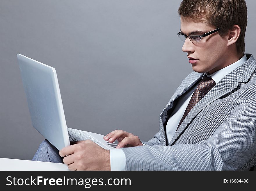 A young man in a suit with a laptop. A young man in a suit with a laptop