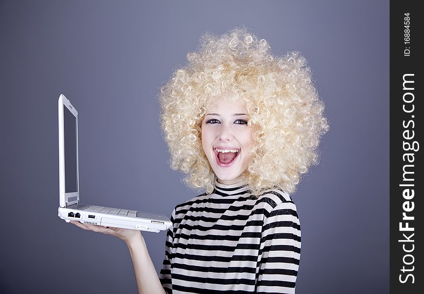 Portrait of funny girl in blonde wig with laptop. Studio shot.