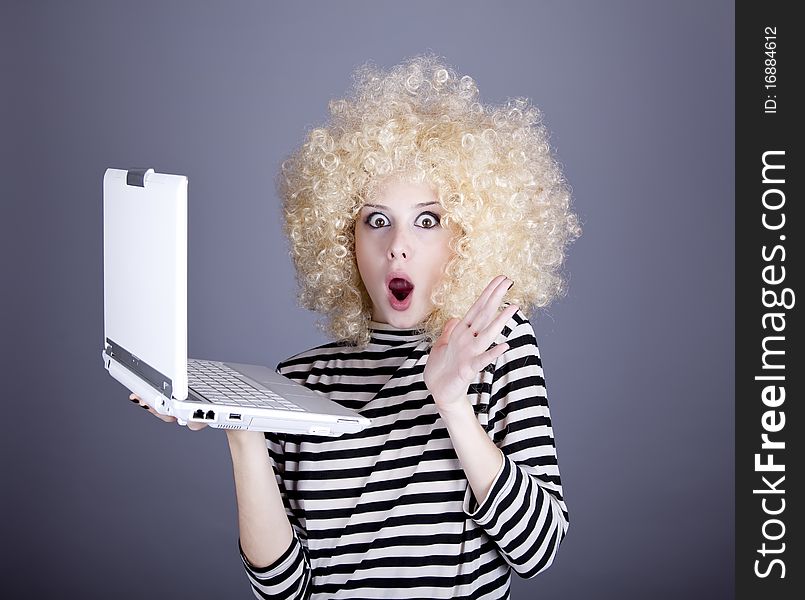 Portrait of funny girl in blonde wig with laptop. Studio shot.