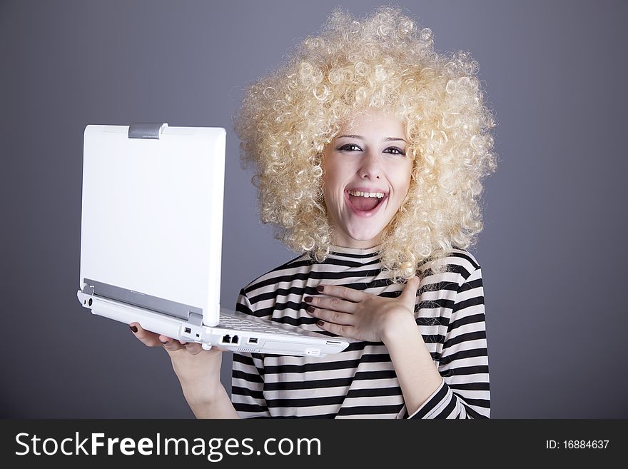 Portrait of funny girl in blonde wig with laptop. Studio shot.