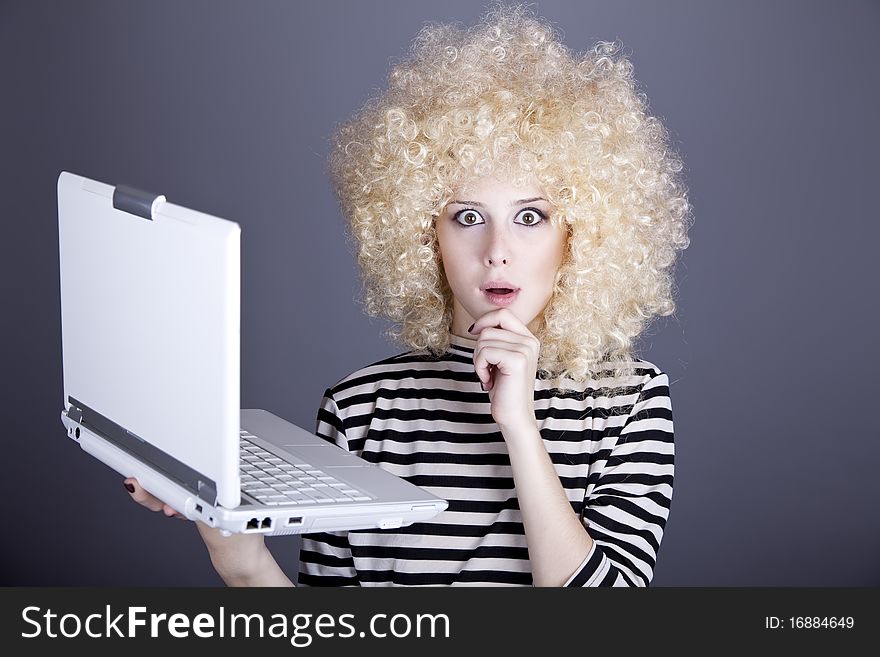 Portrait of funny girl in blonde wig with laptop. Studio shot.