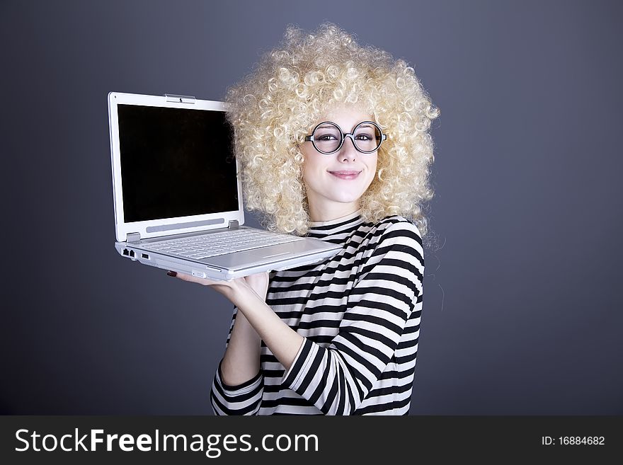 Portrait of funny girl in blonde wig with laptop. Studio shot.