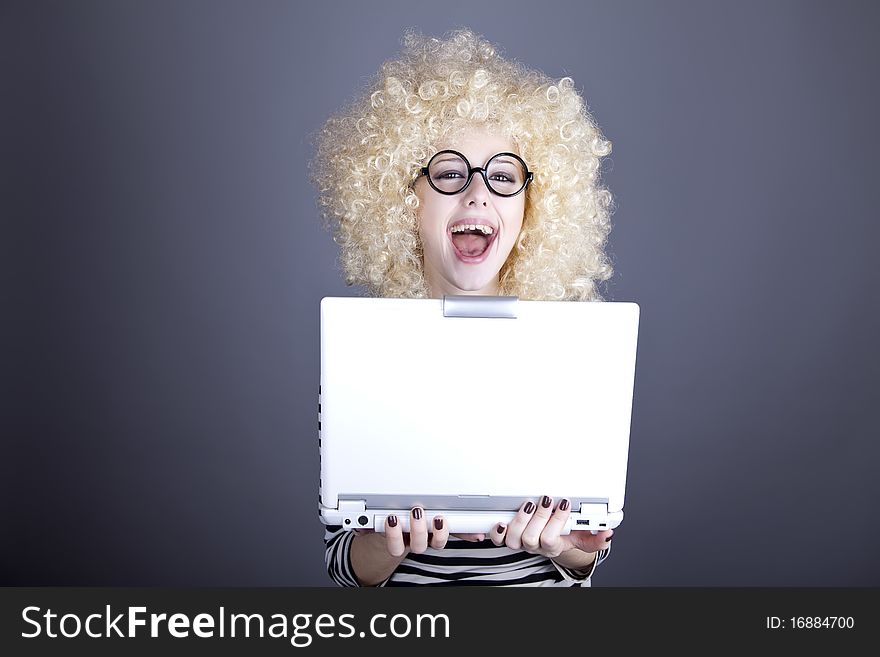 Portrait of funny girl in blonde wig with laptop. Studio shot.