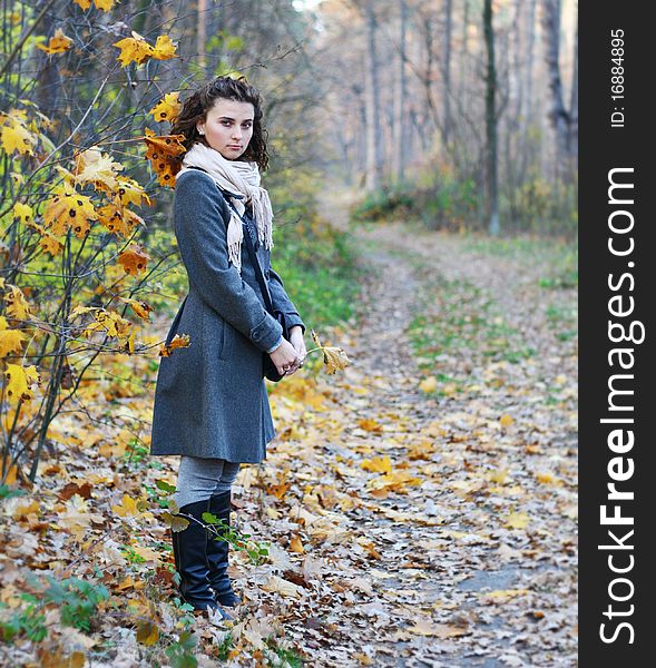 Pretty young girl in autumn fores in coat