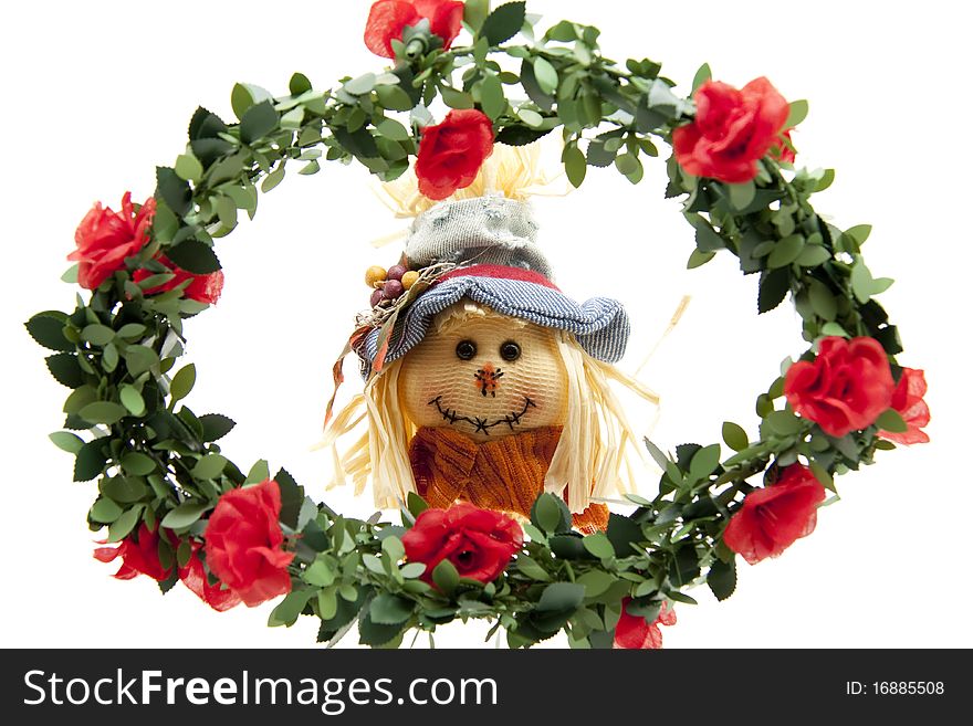 Straw doll behind wreath with roses