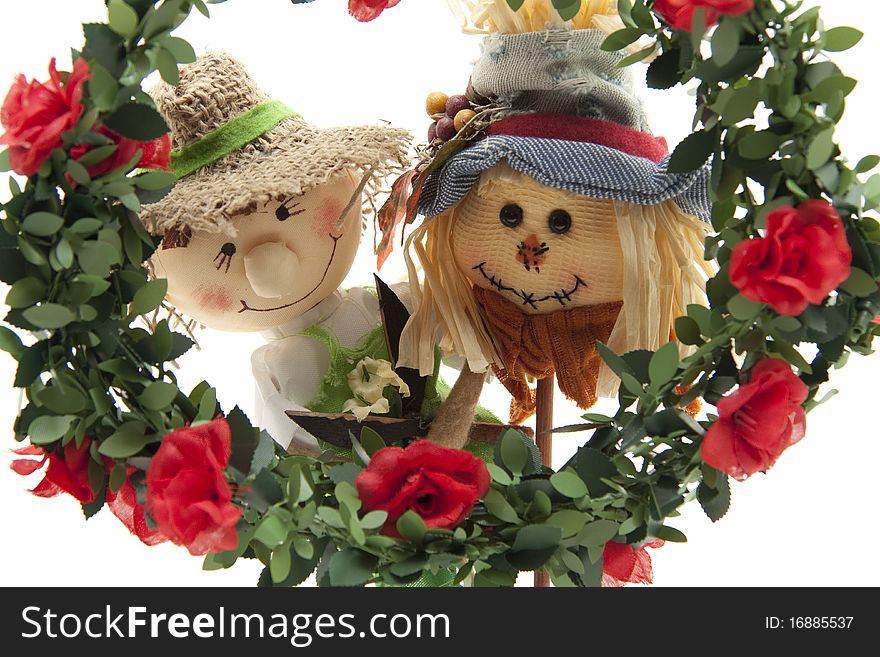 Straw dolls behind wreath with roses. Straw dolls behind wreath with roses