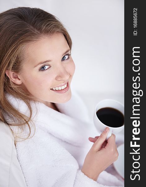 Beautiful girl in a bathrobe with a cup of coffee