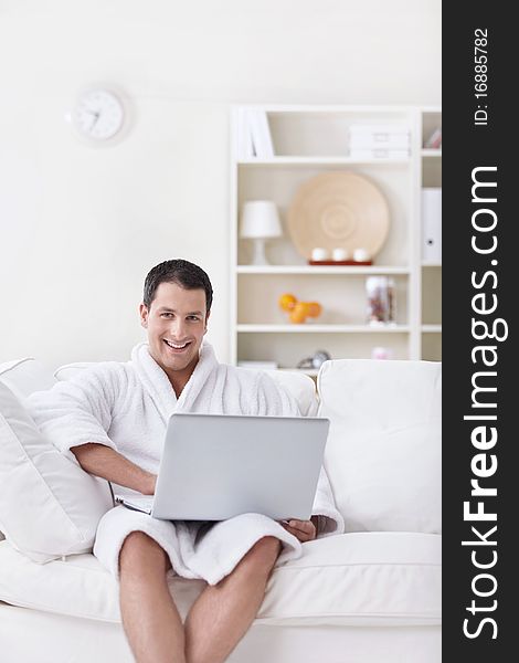 A young man in a white robe with laptop. A young man in a white robe with laptop
