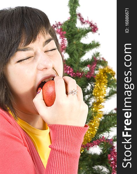 Young woman eating apple under the christmas tree