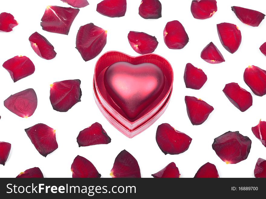 Red heart in box and petals on white background