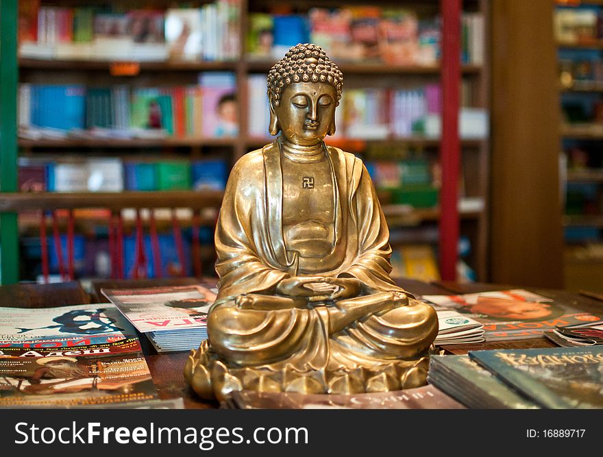 A golden Buddha, siting on the table with yoga magazines. A golden Buddha, siting on the table with yoga magazines
