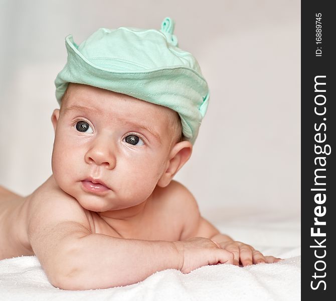 Baby in a cap lying on the bed