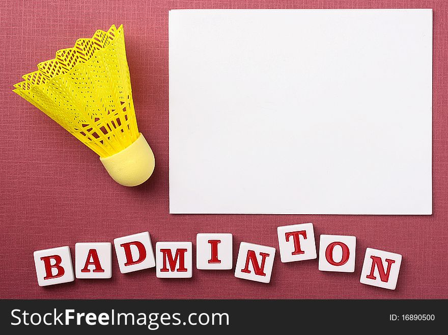 A yellow synthetic badminton shuttlecock next to a white piece of paper to which you can add your text.