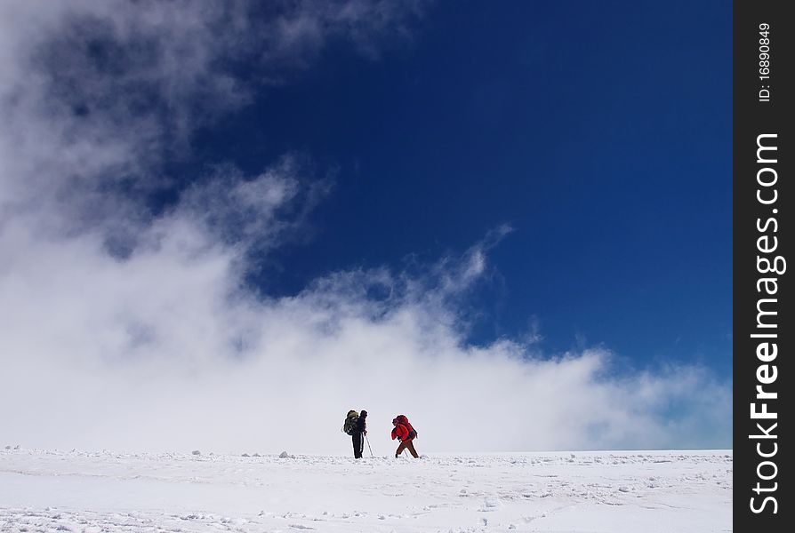Tourists on snow declivity on background blue sky and cloud