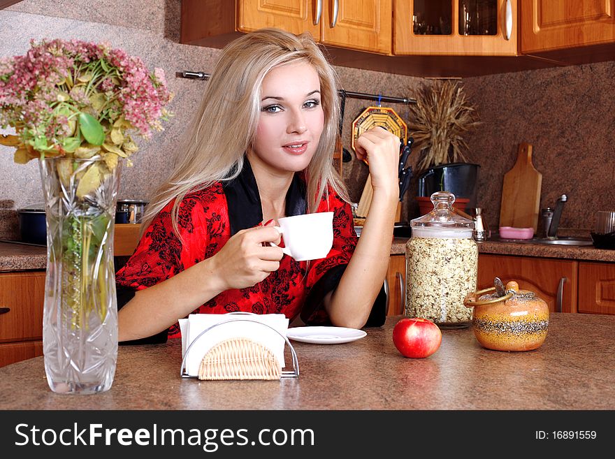 Woman breakfast with apple and cup of hot drink in the kitchen