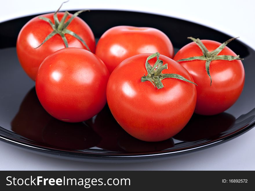 Red tomatoes on black plate