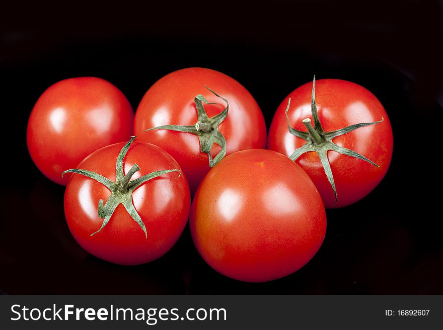 Red tomatoes on black background