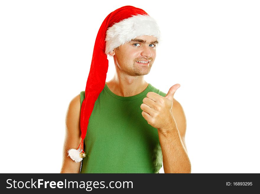 Young man in a Santa Claus hat and green poppy approvingly shows the thumb raised up. Isolated on a white background. Young man in a Santa Claus hat and green poppy approvingly shows the thumb raised up. Isolated on a white background