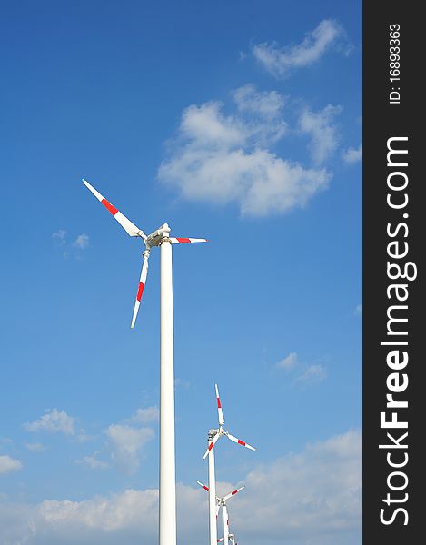 Wind turbines with red color on blue sky background