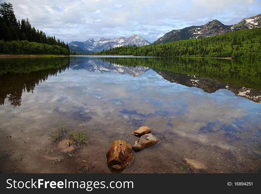 Mountain lake in the Spring with clouds with snow covered mountains reflected in the lake
