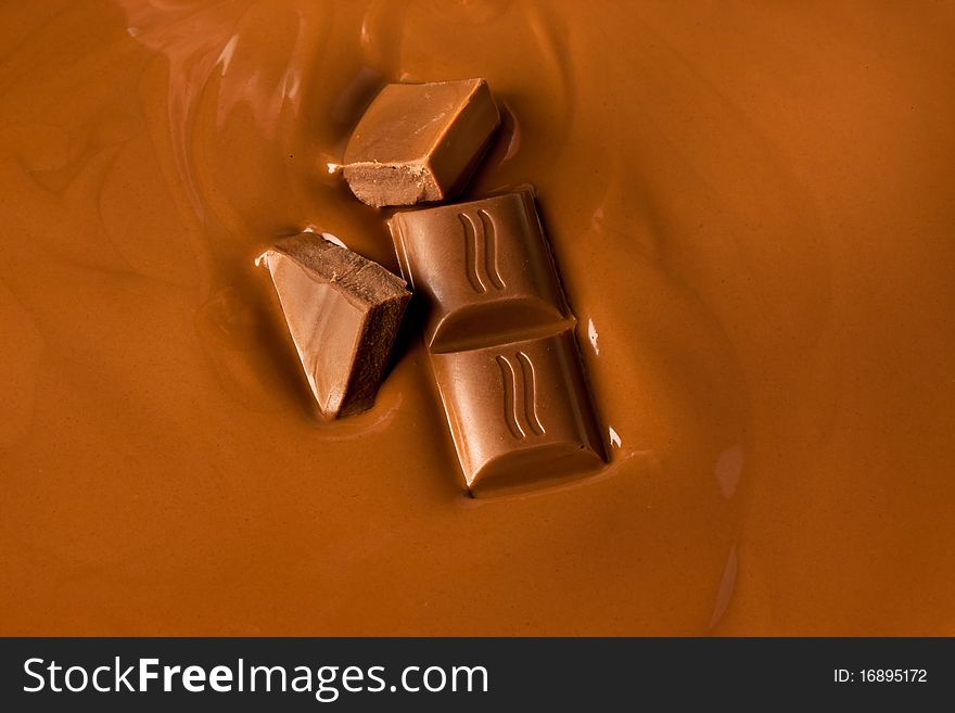 Liquid chocolate with individual pieces slowly sinking into it. Liquid chocolate with individual pieces slowly sinking into it