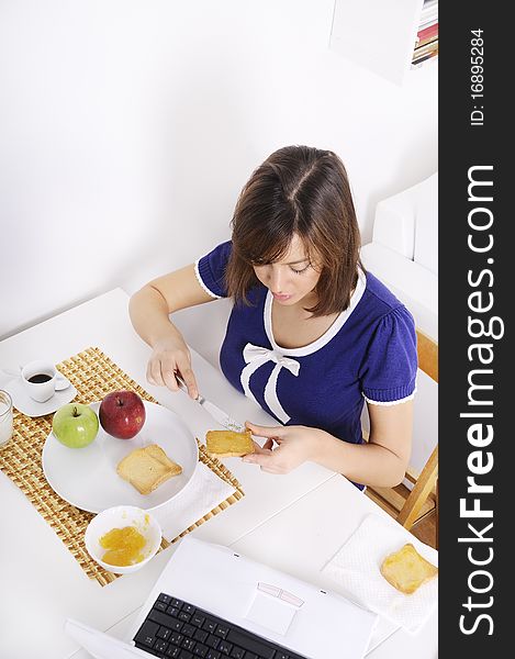 Young woman in breakfast, eating and using laptop. Young woman in breakfast, eating and using laptop