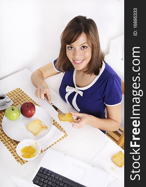 Young woman in breakfast, eating and using laptop. Young woman in breakfast, eating and using laptop