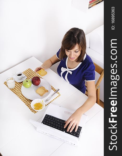 Young woman in breakfast, eating and using laptop. Young woman in breakfast, eating and using laptop