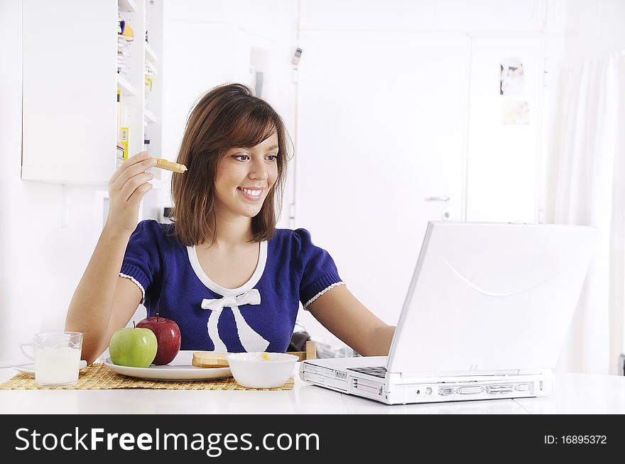 Young woman in breakfast, eating and using laptop. Young woman in breakfast, eating and using laptop