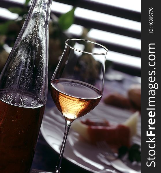 Glass and bottle of rose wine and food in the background. Glass and bottle of rose wine and food in the background